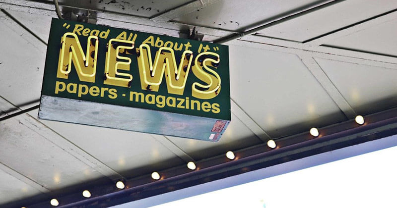 Sign displays "read all about it," advertising newspapers and magazines.