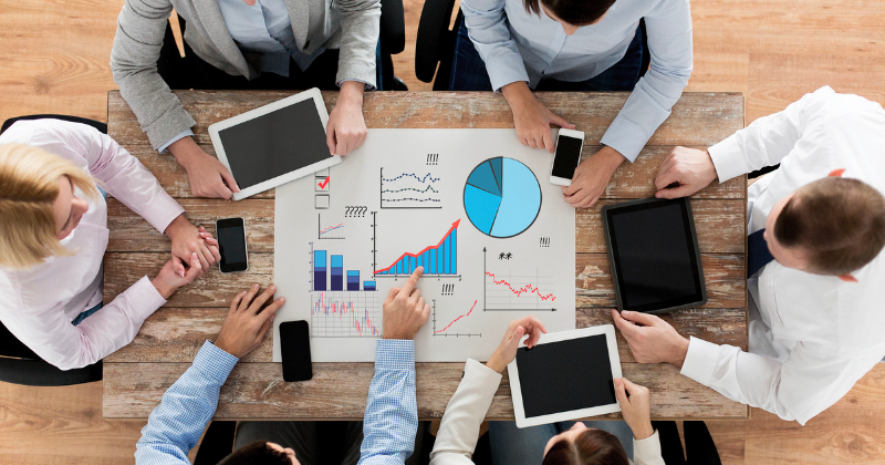 Professionals analyzing data and analytics around a table.